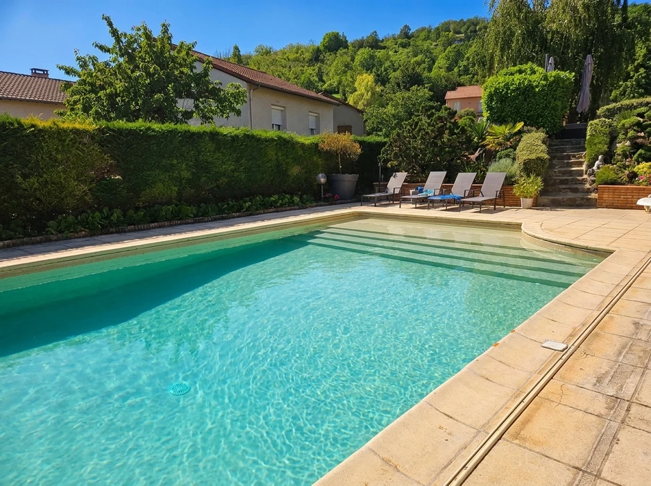Piscine extérieure rectangulaire aux eaux turquoise cristallines, entourée d'un dallage en pierre calcaire beige