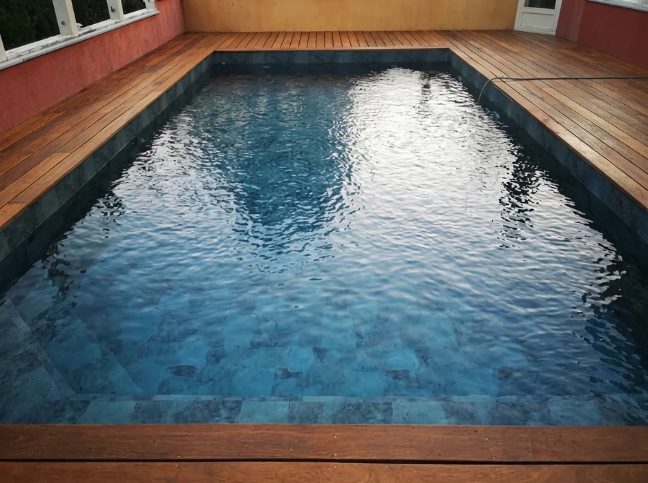 Piscine rectangulaire extérieure vue en perspective, entourée d'une terrasse en bois composite IPE