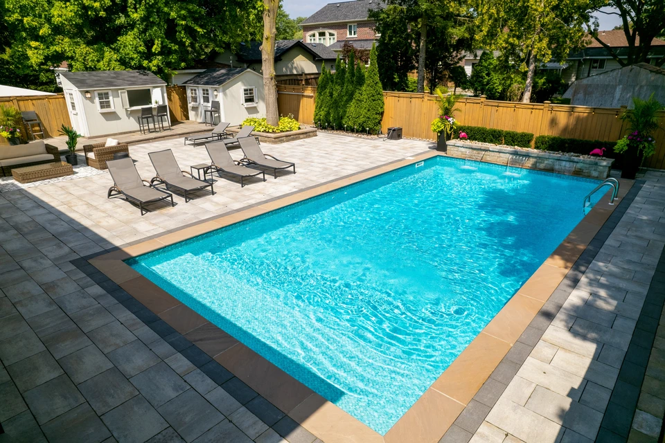 Piscine rectangulaire extérieure vue en perspective, entourée d'une terrasse en bois composite IPE