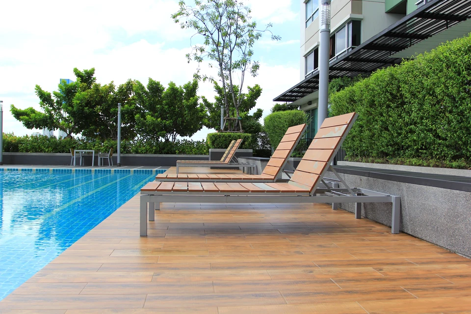 Piscine rectangulaire extérieure en cours de rénovation, bâche de hivernage grise partiellement déroulée depuis un enrouleur tubulaire en PVC