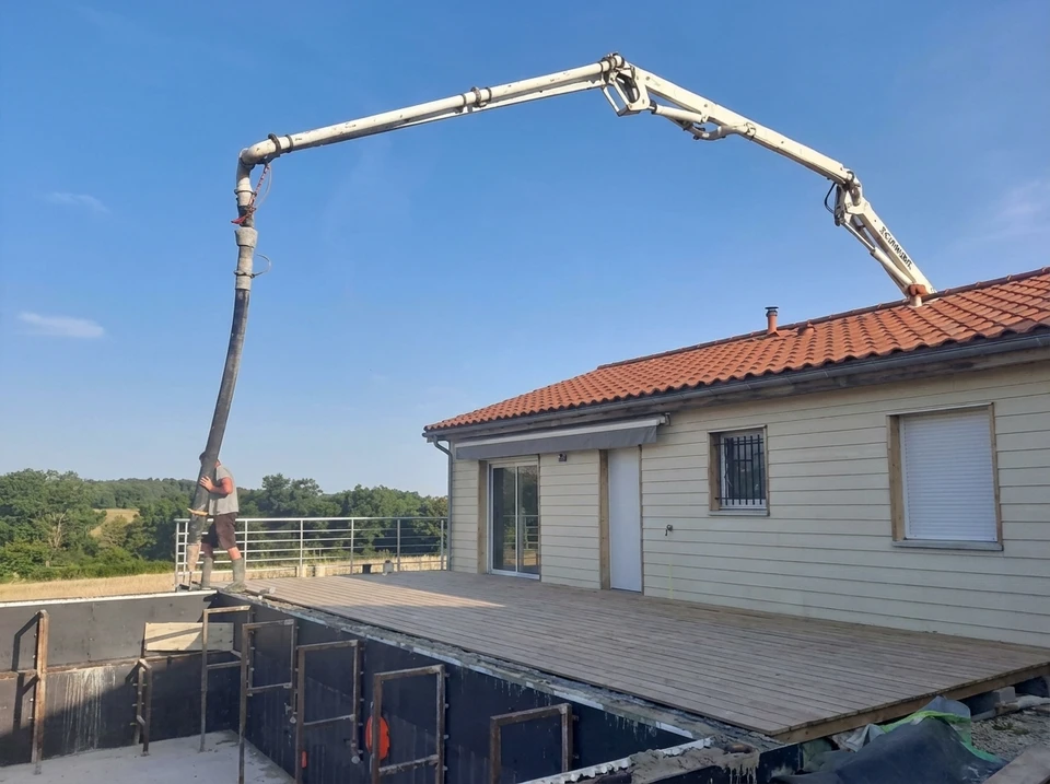 Construction d'une piscine enterrée en cours, vue extérieure, cadre montagneux verdoyant